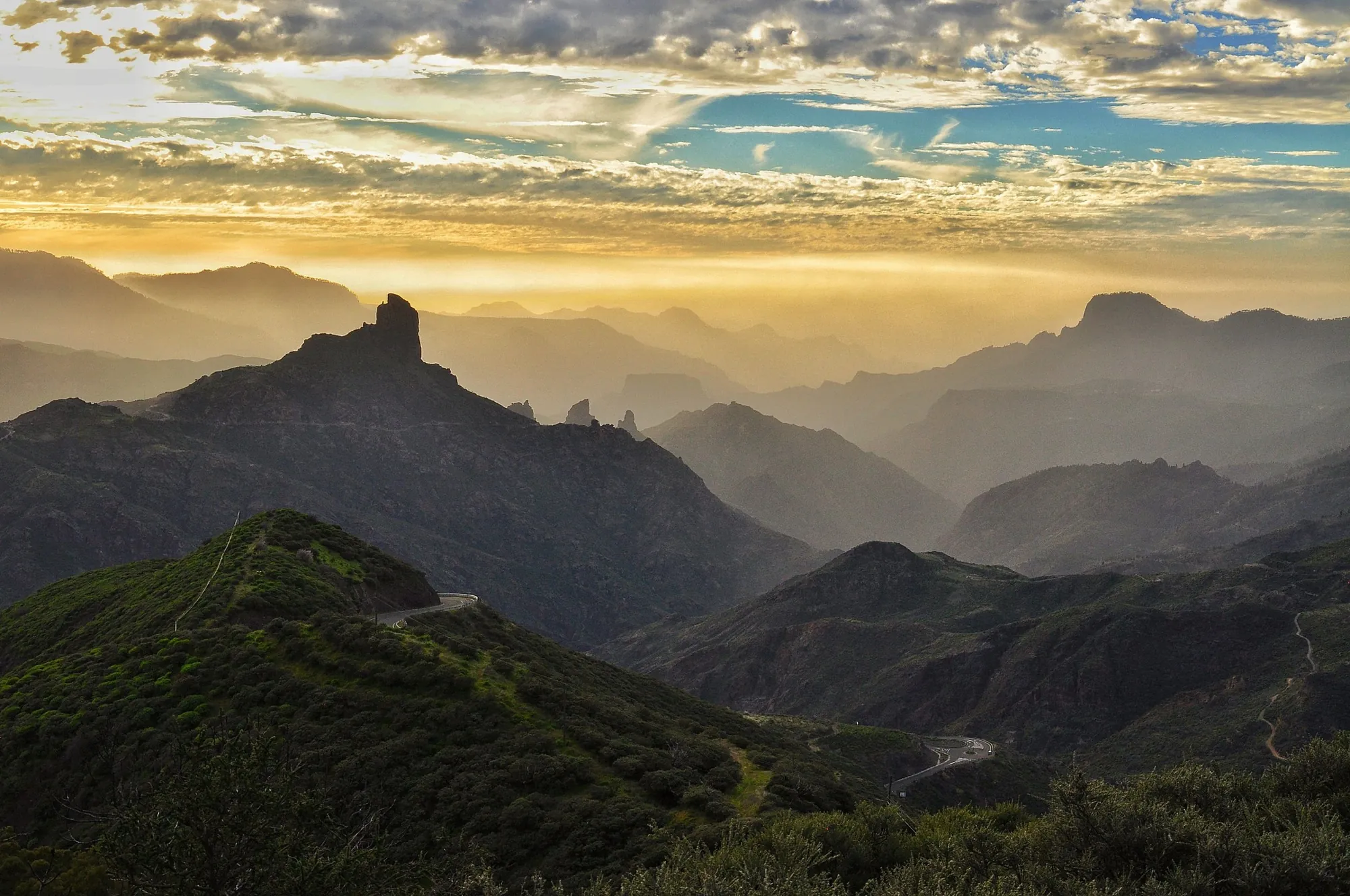 Mountain ridges in golden haze, with the rock tower of Roque Bentayga on the skyline