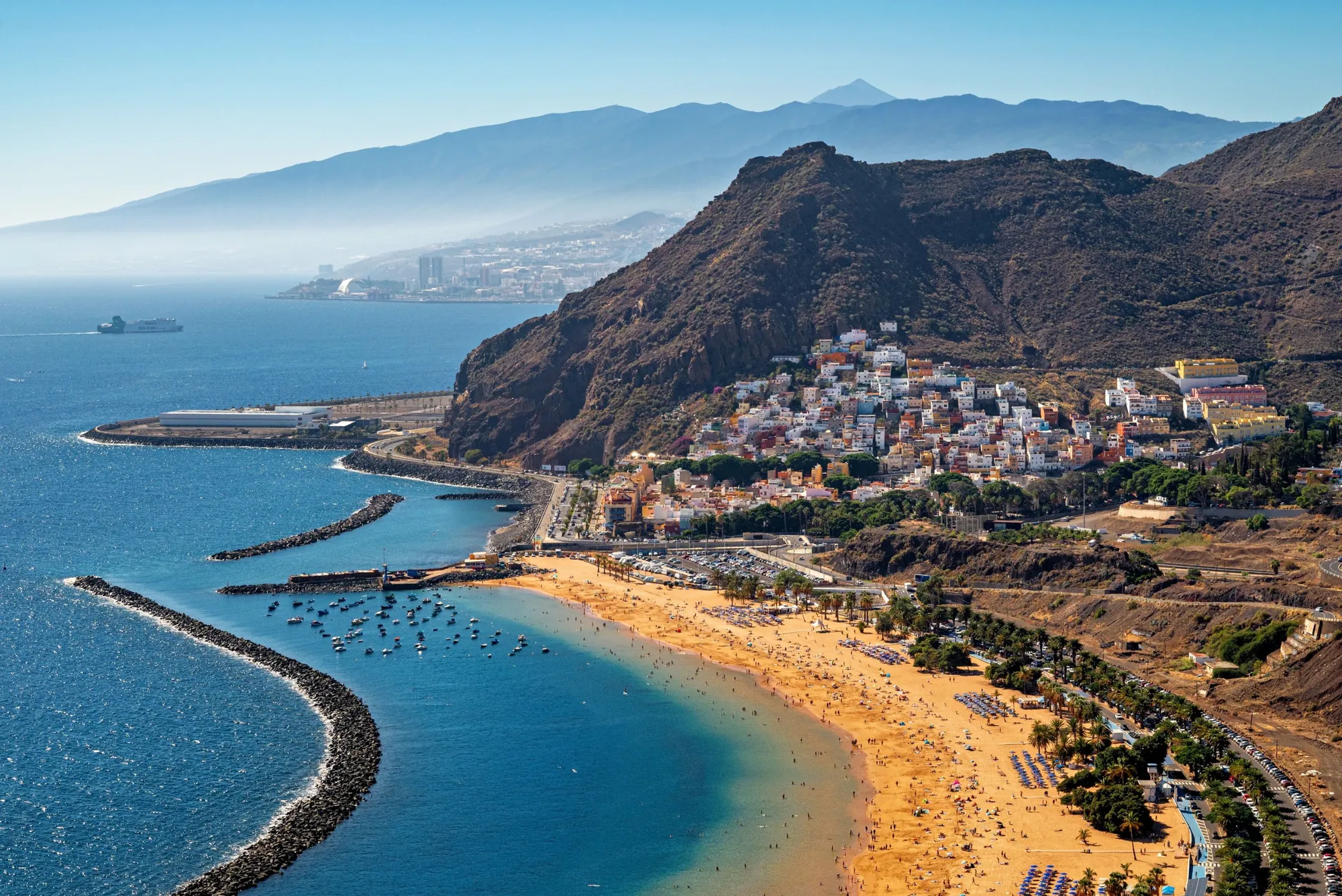 A long golden beach and a harbour of small boats below the village of San Andrés, with Teide in the distance
