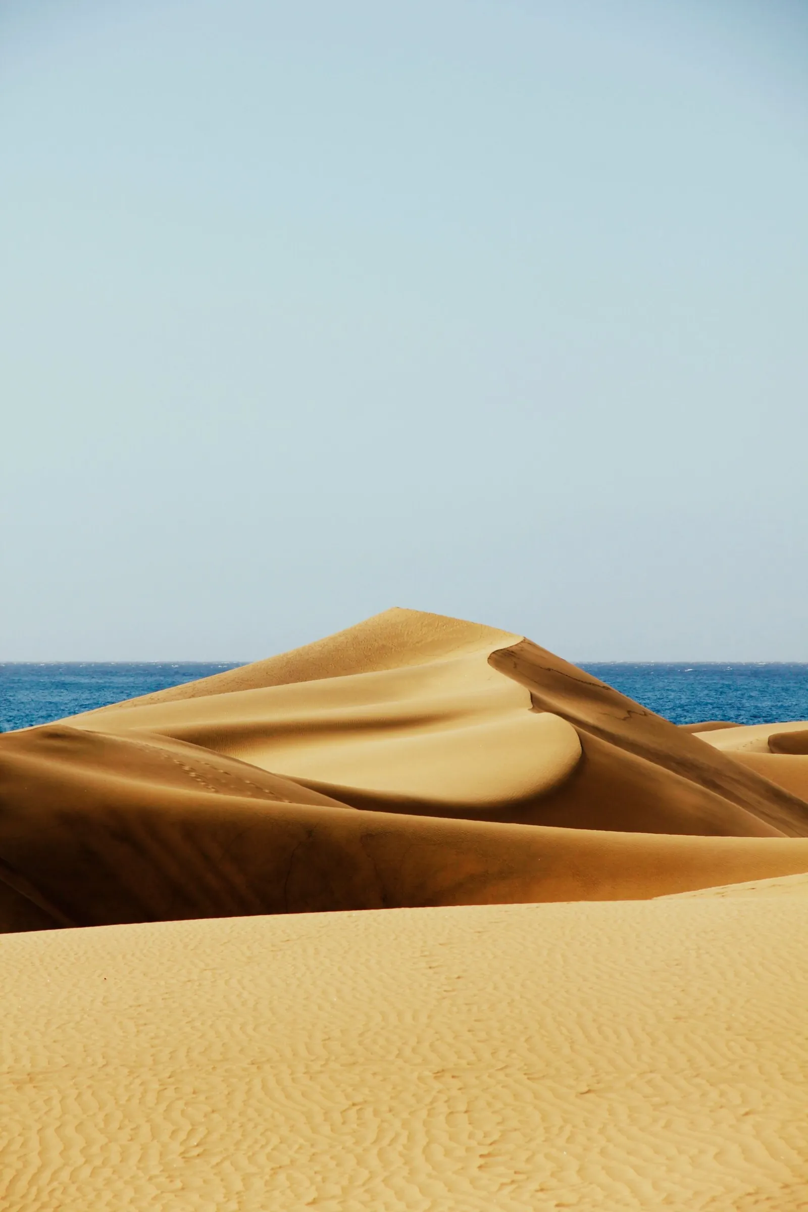 A single sand dune peak in front of the blue sea at Maspalomas